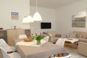 Una sala moderna con comedor, muebles blancos y obras de arte en las paredes.