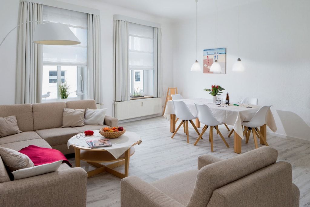 A modern living room with a sofa, coffee table, and dining area with chairs.