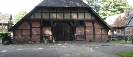 Il s’agit d’un bâtiment traditionnel à colombages, doté d’un toit à forte pente, d’une grande porte en bois et d’une allée pavée.