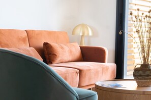 A living room with a sofa, a lamp, and a table with a basket.