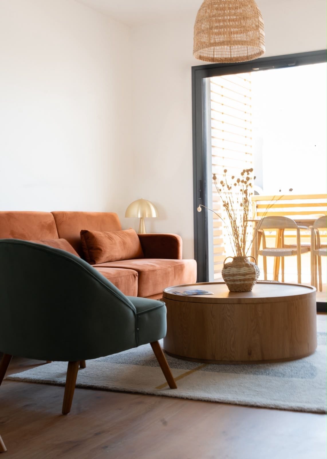 Een moderne woonkamer met een bank, een ronde houten salontafel en een hanglamp.