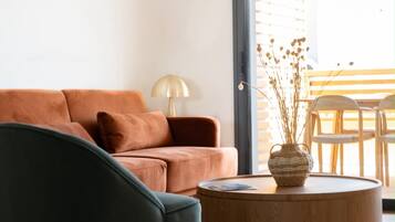Een moderne woonkamer met een bank, een ronde houten salontafel en een hanglamp.