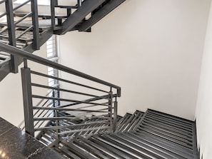 A modern staircase with metal railings and a black floor.