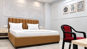 A modern hotel room with a large bed, a red chair, a small table, and artwork on the walls.