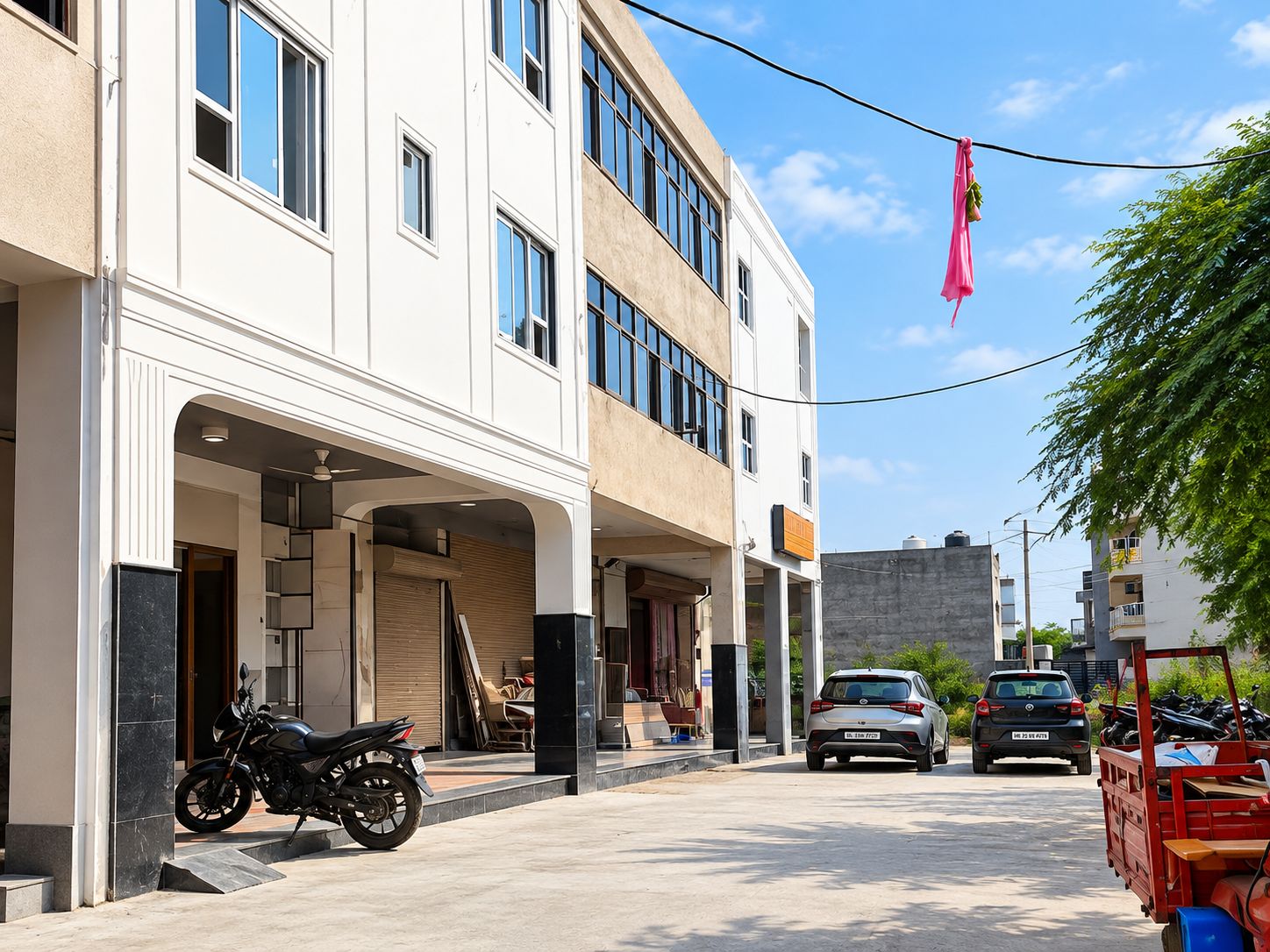 A street view with a building featuring a covered entrance, a parked motorcycle, and a red delivery truck.