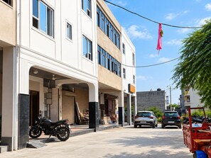A street view with a building featuring a covered entrance, a parked motorcycle, and a red delivery truck.