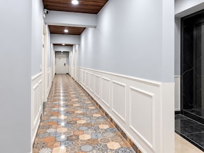 A hallway with patterned flooring, white wainscoting, and a black marble staircase.