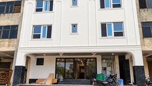 A multi-story building with a central entrance, steps leading up to it, and a few parked motorcycles.