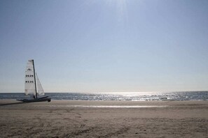 Uma praia com um veleiro na areia e o oceano ao fundo.