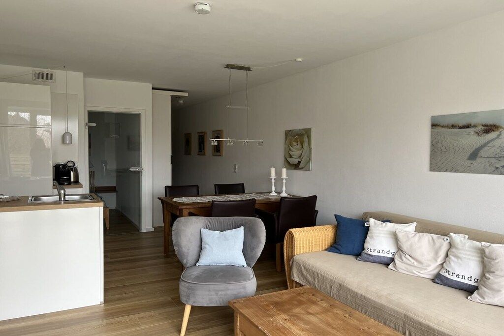 Ein modernes Wohnzimmer mit einer Couch, einem Couchtisch und einem Essbereich mit Tisch und Stühlen.