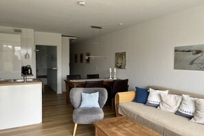 Ein modernes Wohnzimmer mit einer Couch, einem Couchtisch und einem Essbereich mit Tisch und Stühlen.