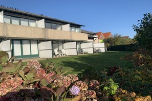Ein zweistöckiges Gebäude mit flachem Dach, großen Fenstern und einem gepflegten Rasen.