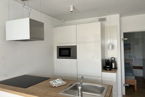 Eine kleine Küche mit Mikrowelle, Kaffeemaschine und Spüle.