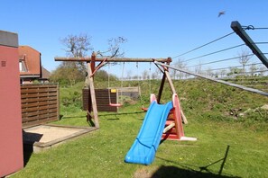 Ein Spielplatz mit Rutsche, Schaukeln und einer Kletteranlage.