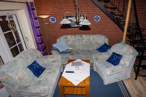 Ein Wohnzimmer mit zwei gemusterten Sofas, einem Holztisch und einer Ziegelwand.