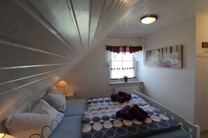 A narrow room with a bunk bed, a window with curtains, a radiator, and a wall-mounted artwork. - Holiday apartment with 1 bedroom (Friedrichskoog-Spitze)
