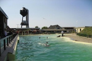 Une zone riveraine avec un plan d’eau, une foule de personnes et une structure imposante.