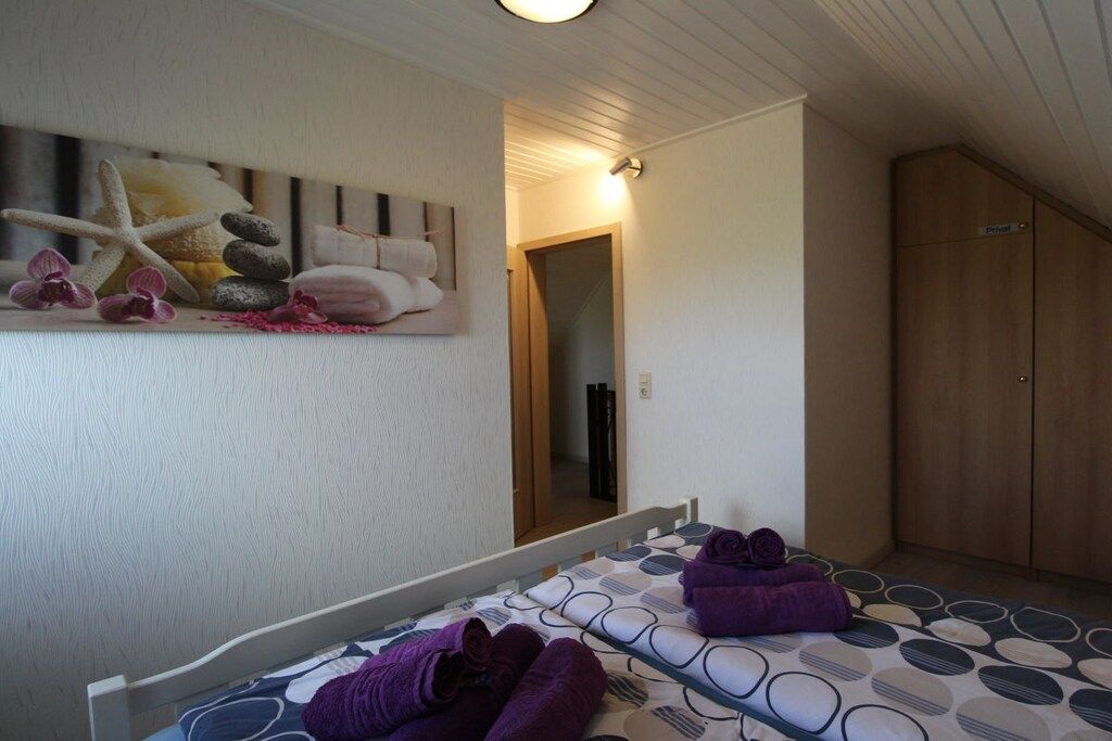 A bedroom with a bed, a wooden wardrobe, and a wall-mounted artwork.