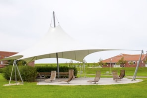 A covered outdoor seating area with benches and a white canopy structure. - Holiday home with 2 bedrooms (Norddeich)