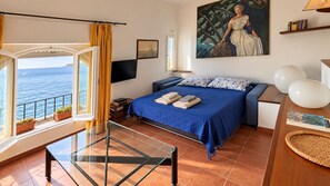 A bedroom with a bed, a TV, a painting, and a view of the sea. - Casa Amanda: A Window to the Sea in Portofino Marine Park (Pedale)
