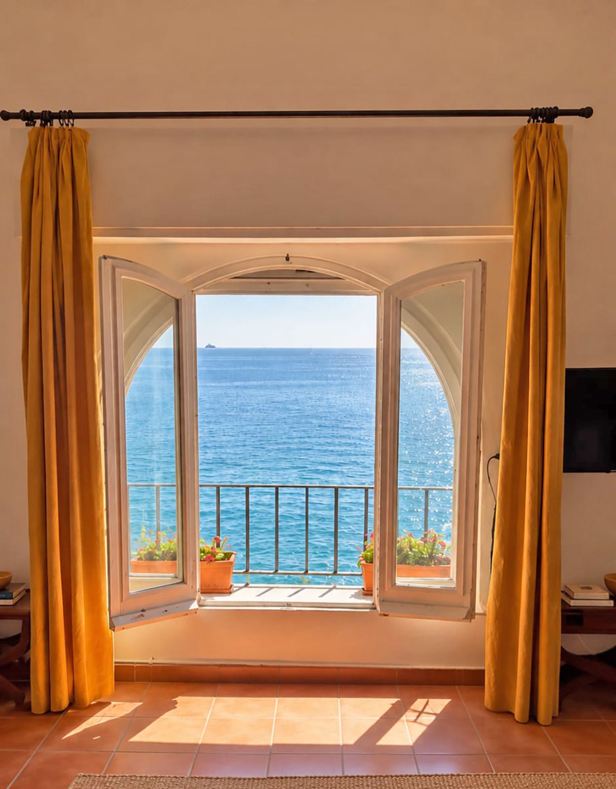 Una stanza con un'ampia finestra panoramica, tende e vista sul mare.
