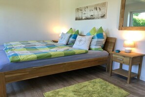 Ein Bett mit kariertem Überwurf, ein Nachttisch mit Lampe und ein Bild an der Wand.