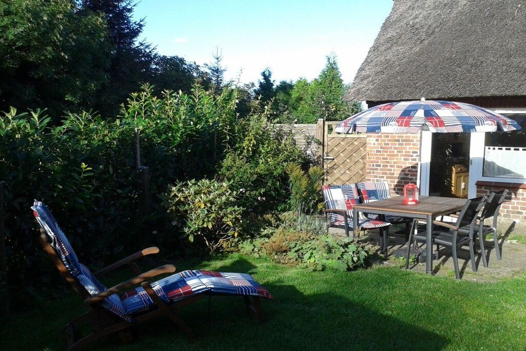 A patio with a table and chairs, a grill, and a chair with a patterned cushion.