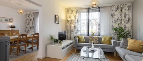 Ein modernes Wohnzimmer mit einer Couch, einem Couchtisch und einem Essbereich mit Stühlen und einem Tisch.