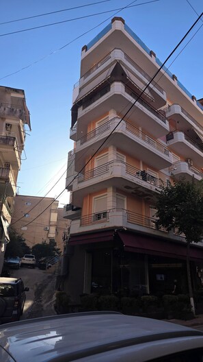 A multi-story building with balconies, a ground-level entrance, and parked cars. - Penthouse · 100 m² terrace · Jacuzzi (Saranda)