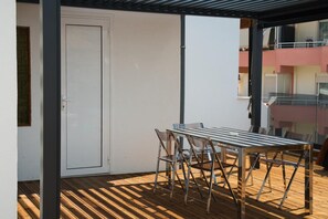 A balcony with a table and chairs, a door, and a view of a building with balconies. - Penthouse · 100 m² terrace · Jacuzzi (Saranda)