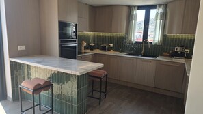 A modern kitchen with a marble countertop, wooden cabinets, and a built-in oven. - Penthouse · 100 m² terrace · Jacuzzi (Saranda)