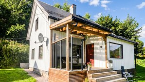 Una casa de una planta con porche, antena parabólica y ventana decorada con forma de corazón.