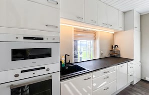 A modern kitchen with built-in appliances, a black countertop, and white cabinetry.