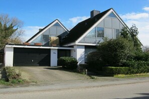 Ein modernes, zweistöckiges Haus mit Garage, großen Fenstern und einem gepflegten Rasen.
