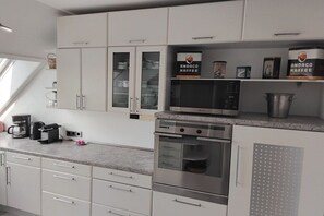 A modern kitchen with white cabinets, a built-in oven, a microwave, and Andaco Kaffe brand coffee machines. - Holiday apartment with 3 bedrooms (Lübeck)