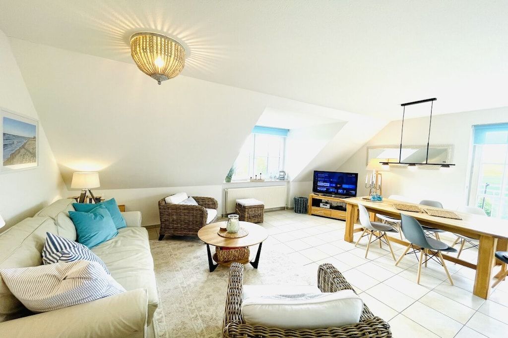 A modern loft-style living space with a high ceiling, a dining area, and a television.