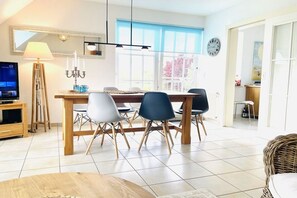A modern living room with a dining area, a television, and a large window. - Holiday apartment with 1 bedroom (Boltenhagen)
