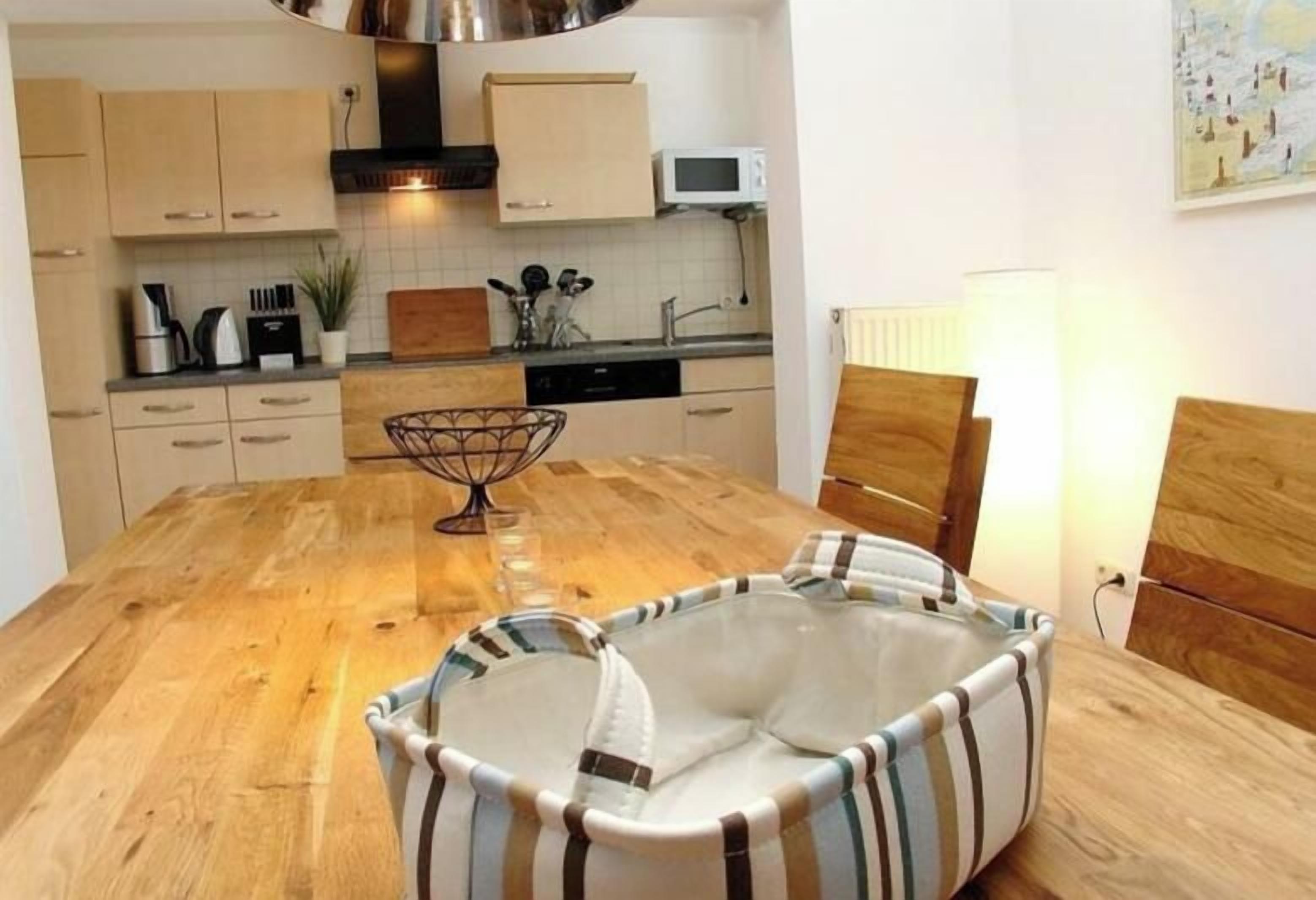 A kitchen with wooden cabinets, a microwave, and a dining table with a striped chair.
