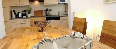 A kitchen with wooden cabinets, a microwave, and a dining table with a striped chair.