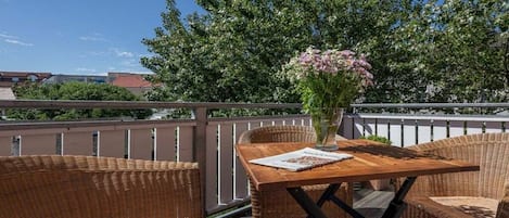 Un patio in legno con mobili in vimini e un vaso di fiori.