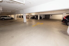 A multi-level parking garage with several cars parked, clear directional arrows on the floor, and visible structural columns. - Marvien - City Stay - Modern 2BR Apartment - Free Garage (Vienna)
