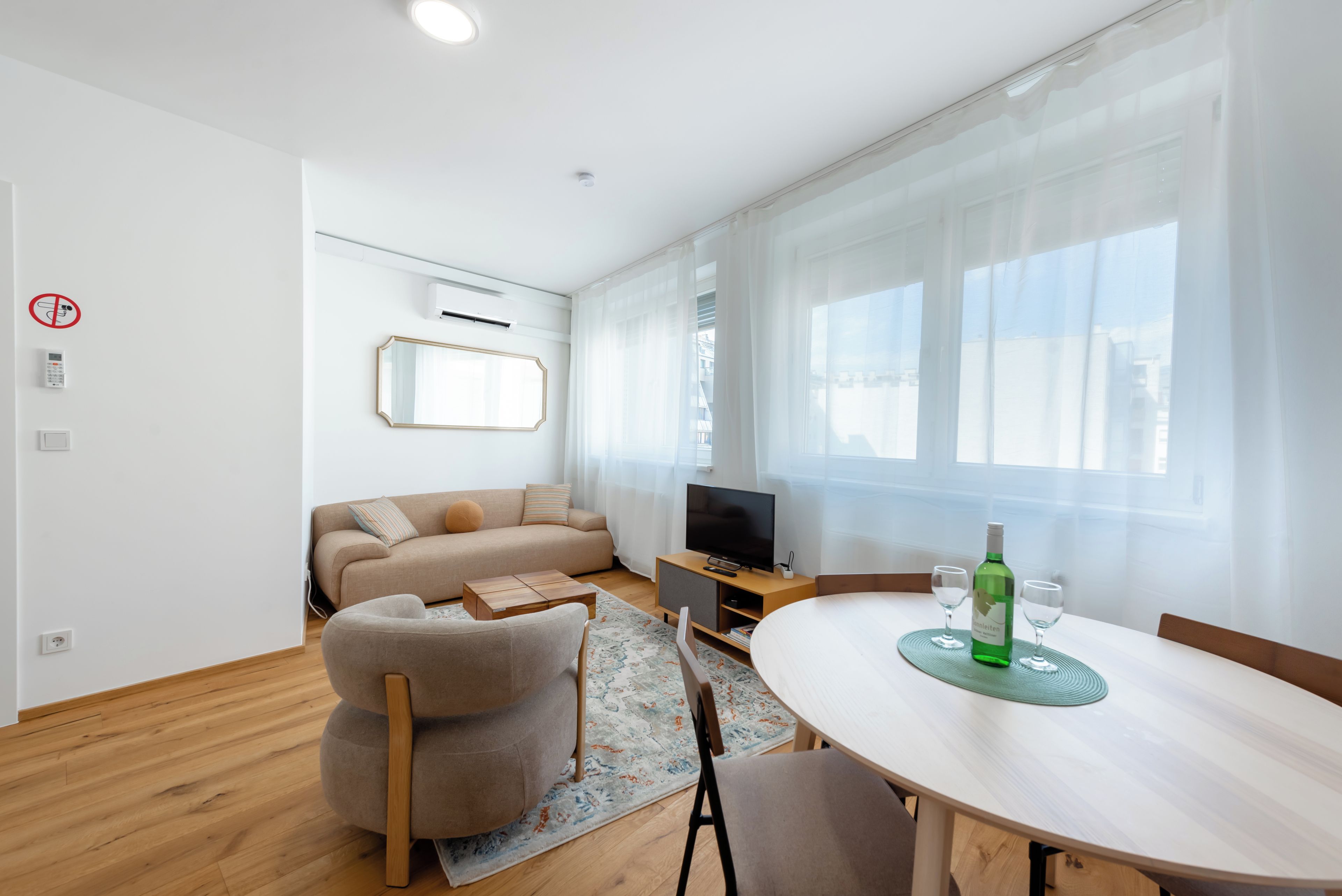 Una sala moderna con un sofá, televisor y una mesa de comedor con sillas.