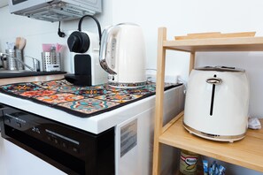 A kitchen with a coffee maker, a toaster, and a patterned tablecloth. - Marvien - City Stay - Modern 2BR Apartment - Free Garage (Vienna)