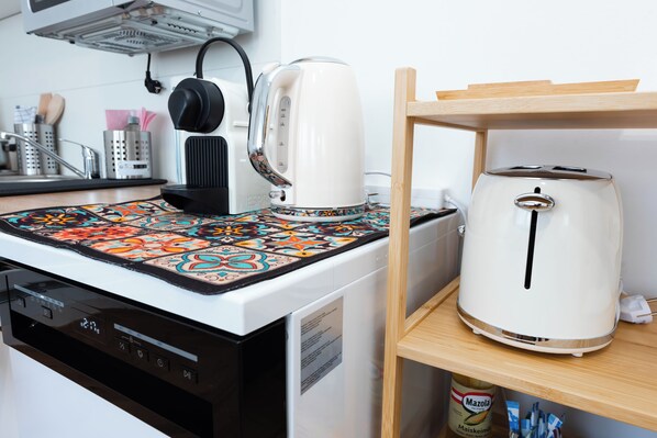 Una cucina con una macchina da caffè, un tostapane e una tovaglia fantasia.