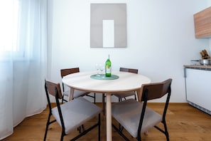 Un tavolo rotondo da pranzo con sei sedie, una bottiglia di vino e due bicchieri su un sottopiattino.