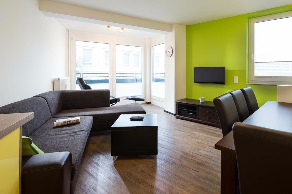 A modern living room with a sofa, coffee table, and dining area.