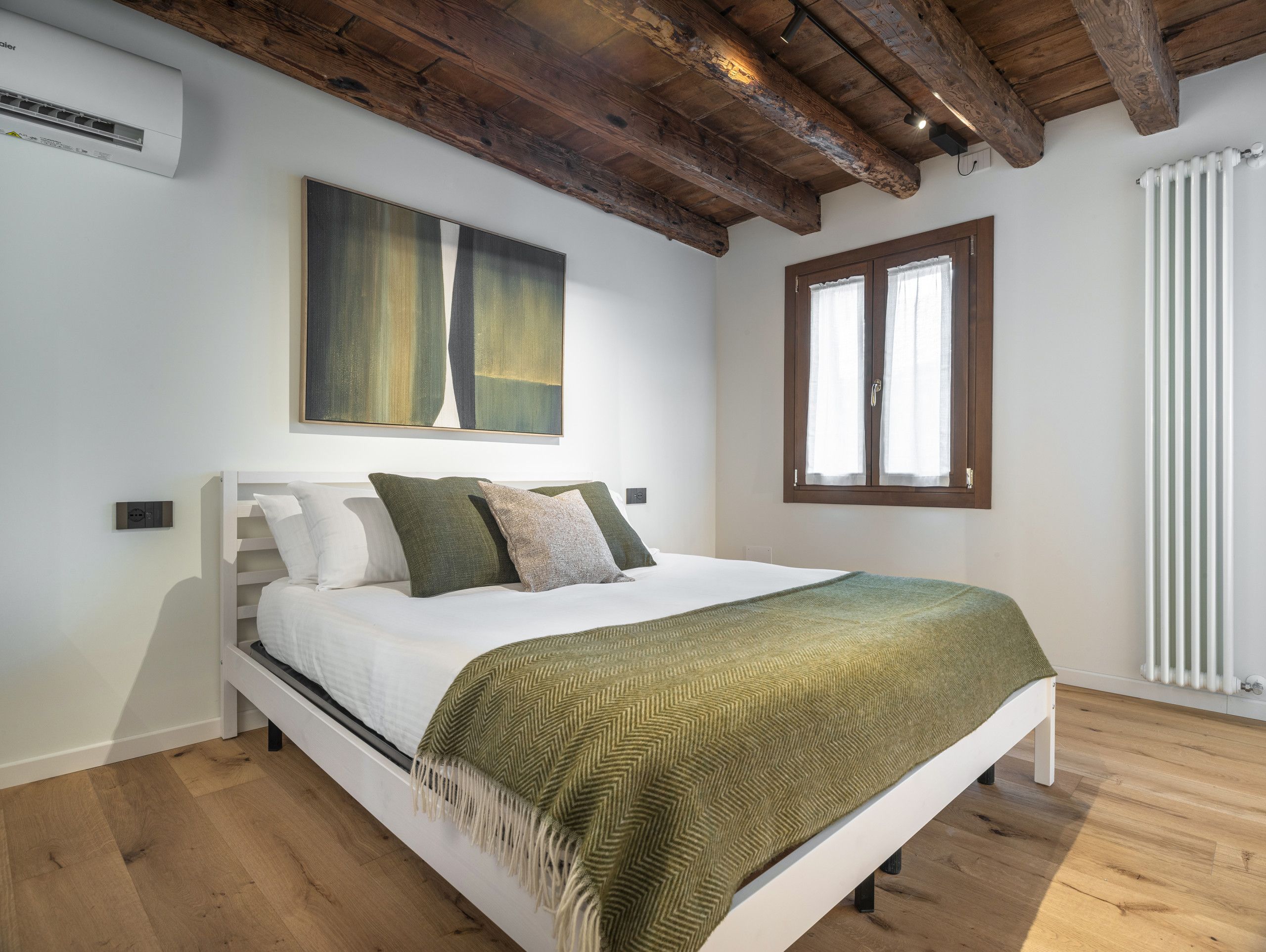 A bedroom with a bed, a window, and a radiator.