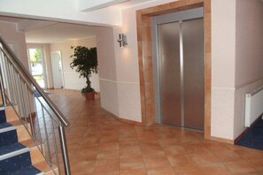 A hallway with a staircase, a potted plant, and a door. - Holiday apartment with 1 bedroom (Bad Zwischenahn)