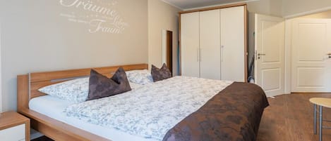 Un dormitorio con cama, mesita de noche, armario y puerta.