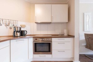 A kitchen with white cabinets, a stainless steel oven, and a coffee maker. - Holiday apartment with 1 bedroom (Bad Zwischenahn)